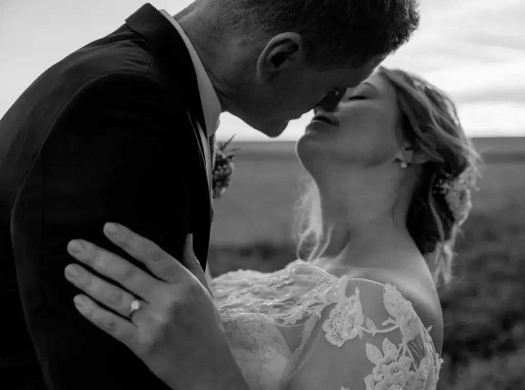 Braut lässt sich fallen und ganz zärtlich vom Bräutigam küssen
