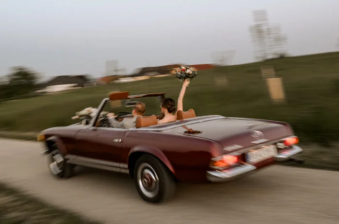 Brautpaar fährt mit einem Oldtimer weg