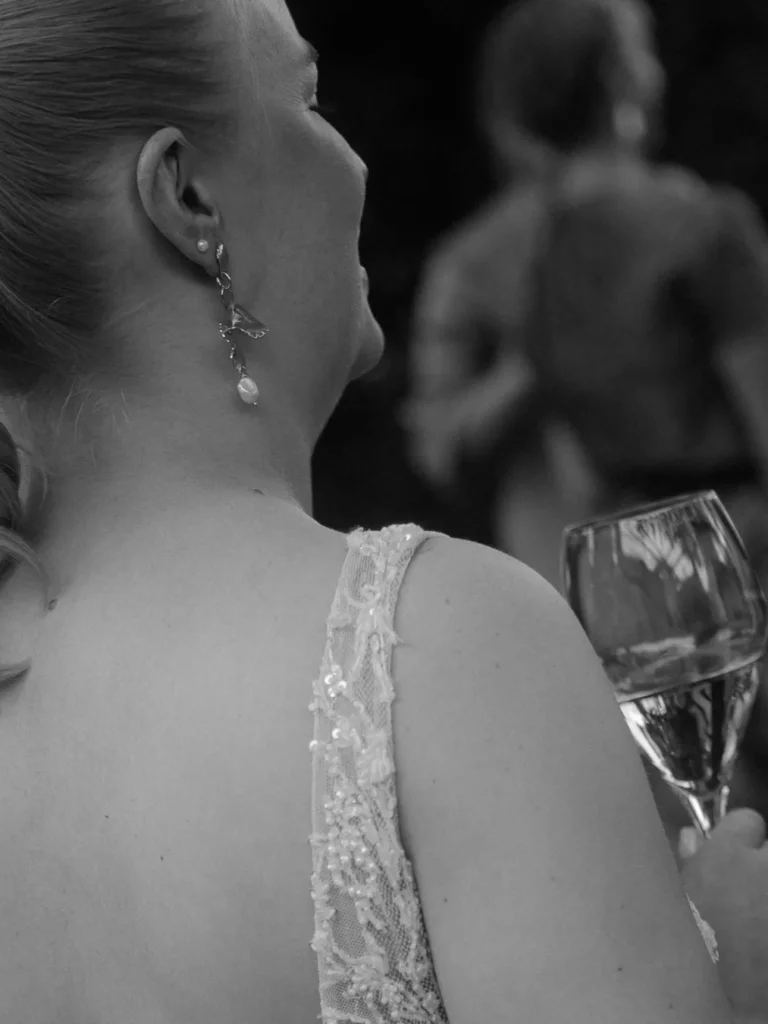 Braut mit einem rückenfreien Kleid und einem Sektglas in der Hand